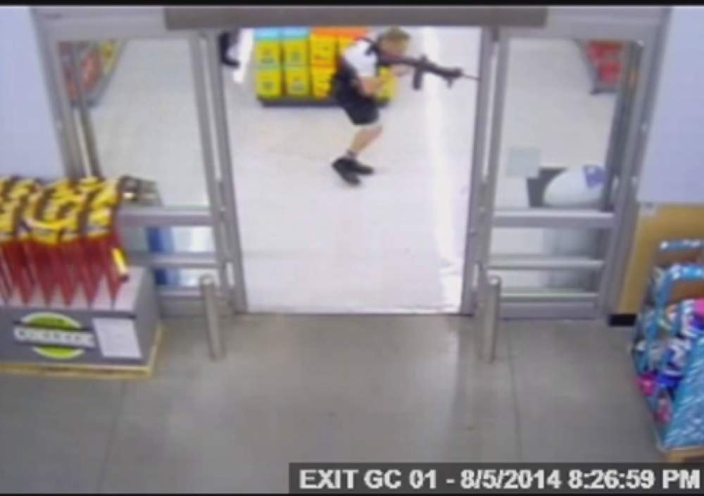 A still frame from Walmart security video shows a Beavercreek police officer moving toward John Crawford III  inside the store on Aug. 5, 2014.