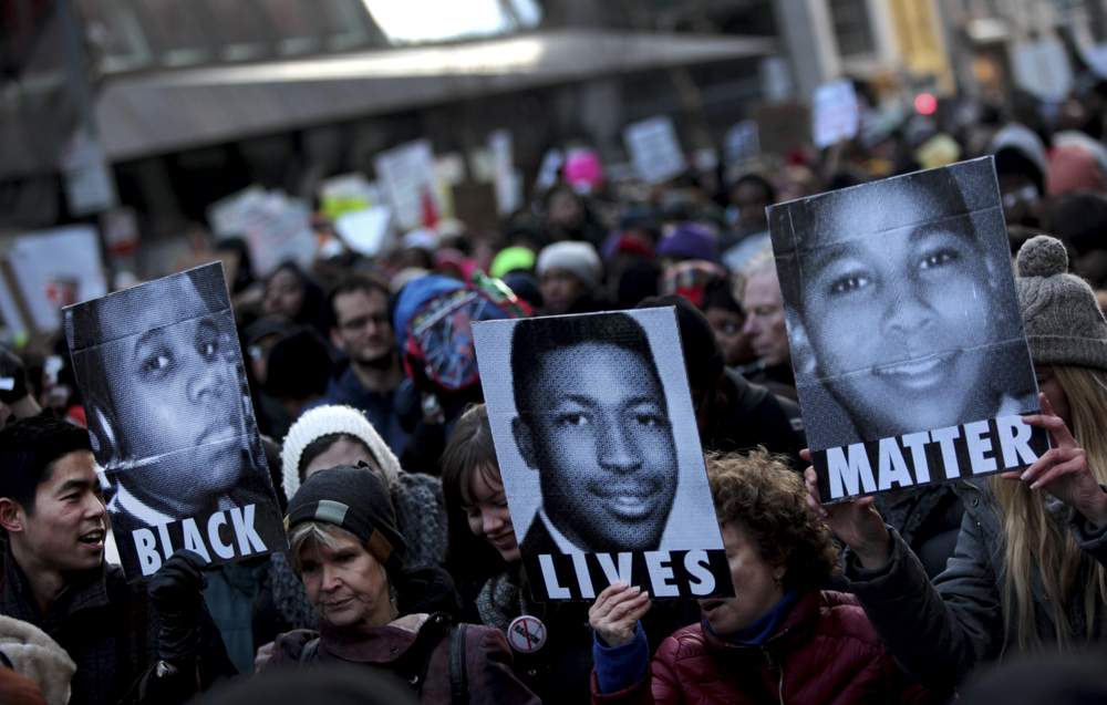 Protesters hold images of Michael Brown, left, Eric Garner and Tamir Rice, right, during a march in New York, Dec. 13, 2014. YANA PASKOVA / NEW YORK TIMES