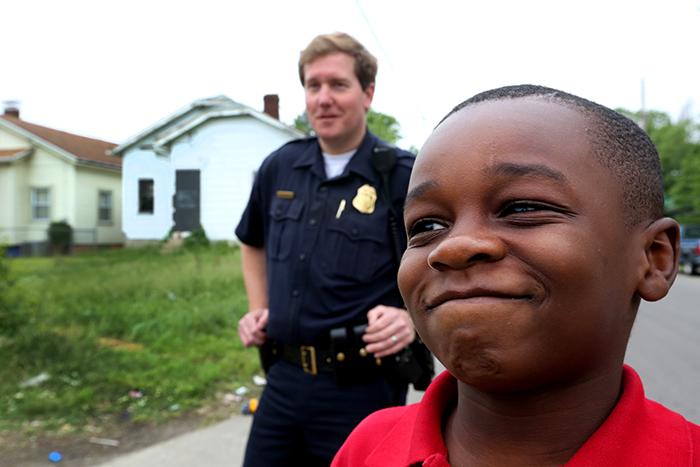 "Any time they shoot, my mom yells, 'Everybody get on the ground,’” says Jeremiah Hudson Davis, 9, while Dayton Police Sgt. John Riegel watches his friends play basketball. LISA POWELL / STAFF
